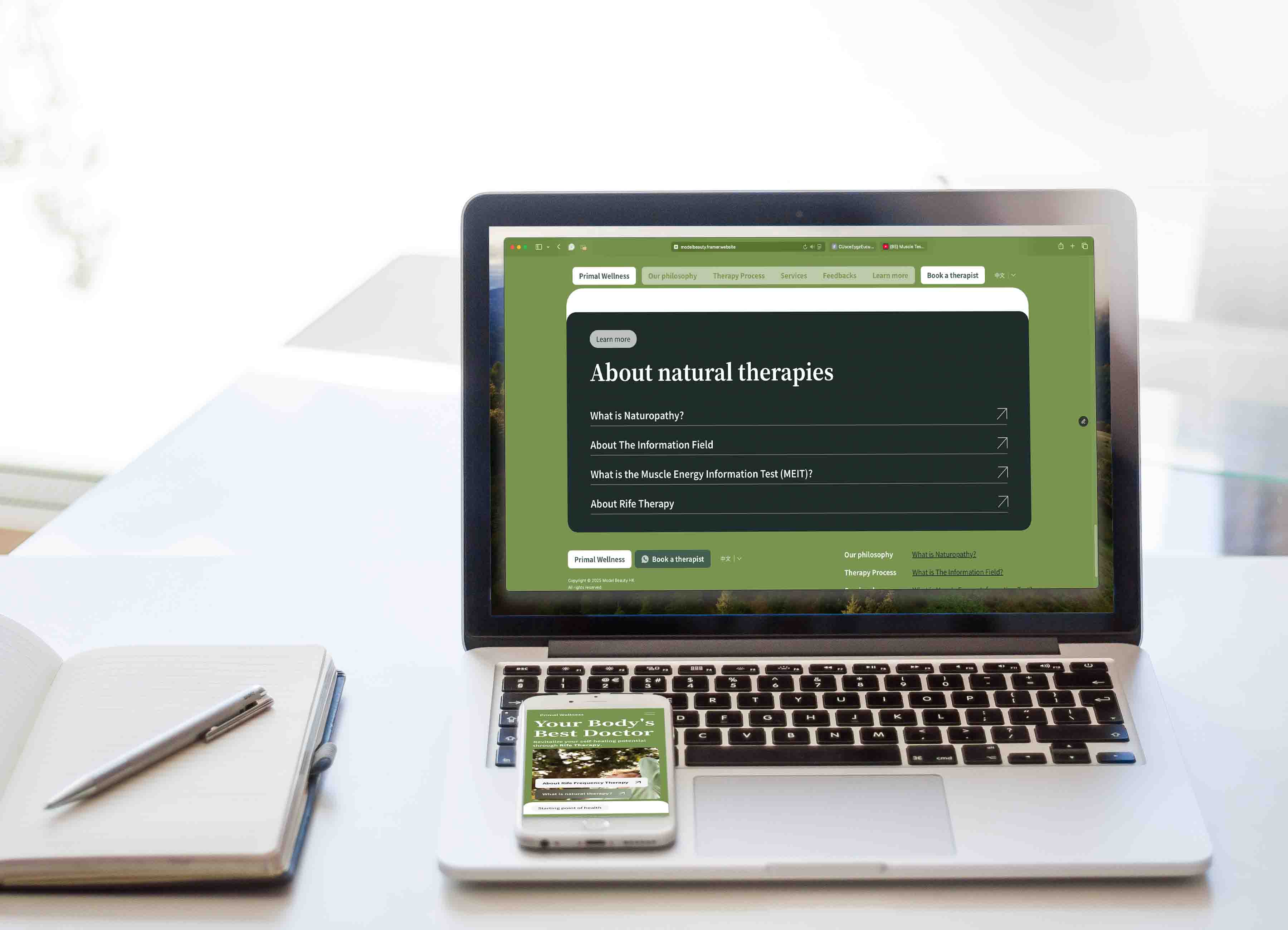 A laptop on a desk displays a Primal Wellness's website, next to an open notebook with a pen and a smartphone showing phone sized website. The bright, tidy scene suggests an organised workspace at the background.